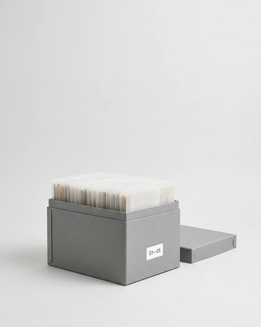 A grey archive box of frosted vellum folders. One folder rises.